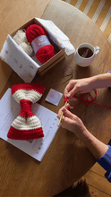 Load image into Gallery viewer, hands making a crocheted Christmas Bow Decoration